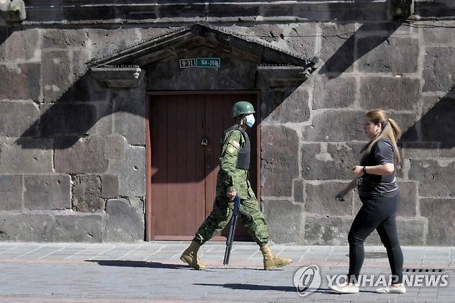 에콰도르 대통령 집무실 인근 경비 강화 (키토 AFP=연합뉴스) 18일(현지시간) 에콰도르 키토 카론델레트 궁(대통령 집무실 및 관저) 앞에서 군 장병이 행인을 지나치고 있다. 전날 기예르모 라소 대통령은 자신의 잔여 임기를 포기하는 국회해산권을 발동했다. 2023.5.19