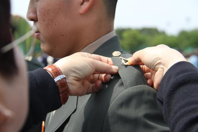 지난 12일 경북 포항 해병대 교육훈련단에서 열린 해병대 부사관 400기 임관식에서 한 후보생 부모가 아들에게 하사 계급장을 달아주고 있다. 포항=뉴시스
