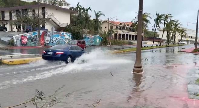시속 241㎞의 돌풍을 동반한 '슈퍼 태풍' 마와르가 태평양의 미국령 괌을 강타한 25일(현지시간) 한 자동차가 투몬 만의 침수된 거리를 지나가고 있다. 당국은 이번 태풍으로 인한 인명 피해는 없으나 전체 5만2천 가구·상업시설 중 1천 곳에만 전기가 공급되는 등 단전 및 단수의 피해가 막대하다고 전했다. [연합]