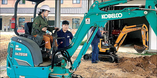 충북도농업기술원 미래농업교육센터에서 김명수 교수(오른쪽)가 이진숙씨에게 굴착기 조작법을 세세하게 알려주고 있다.