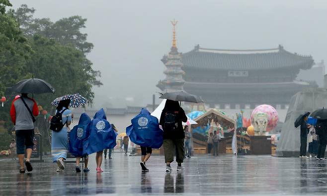부처님 오신 날 연휴를 맞아 빗줄기가 이어지는 가운데 28일 서울 세종대로 광화문광장에서 우산을 쓰고 우비를 입은 시민과 관광객들이 오가고 있다. [사진 출처 = 연합뉴스]