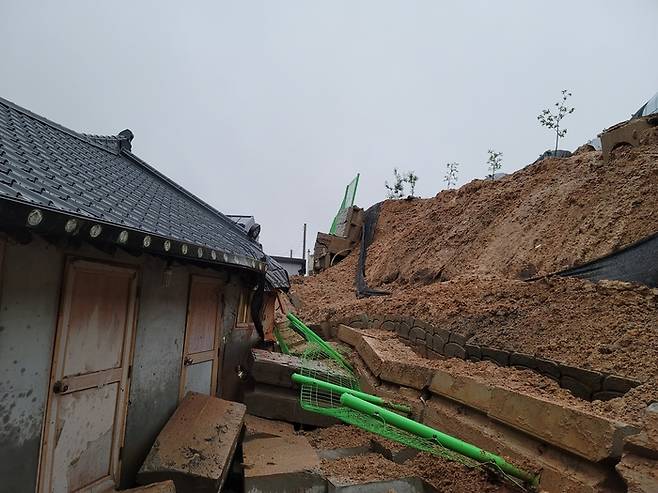전북 지역에 호우 특보가 내려진 29일 오전 완주군 봉동읍 한 주택 인근 축대가 무너져 토사가 흘러내리고 있다. 전북소방본부 제공