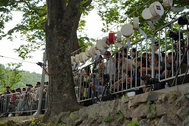 Some visitors sitting behind safety fences had arrived the previous day to reserve a good seat for the Nakhwa Festival. (Lee Si-jin/The Korea Herald)