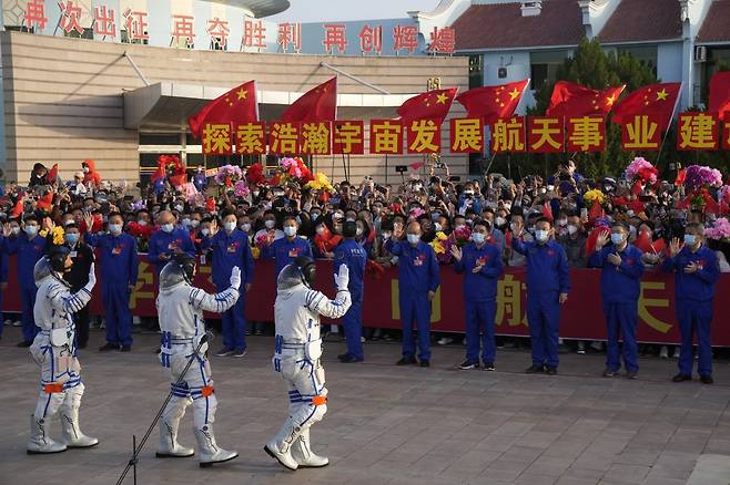 30일 중국 간쑤성 주취안(酒泉) 위성발사센터에서 우주선 탑승을 앞둔 중국 우주비행사 3명이 환영 인파에 인사하고 있다. 주취안=AP 뉴시스