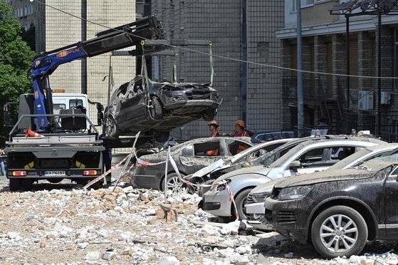 대규모 드론 공격으로 심하게 손상된 러시아의 아파트 건물 옆 주차장에서 공무원들이 파괴된 차량을 제거하고 있다. AFP=연합뉴스