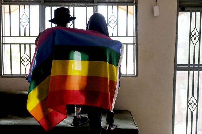 우간다 게이 커플이 지난 3월25일 성소수자를 상징하는 깃발을 몸에 두른 채 포즈를 취하고 있다. AP연합뉴스