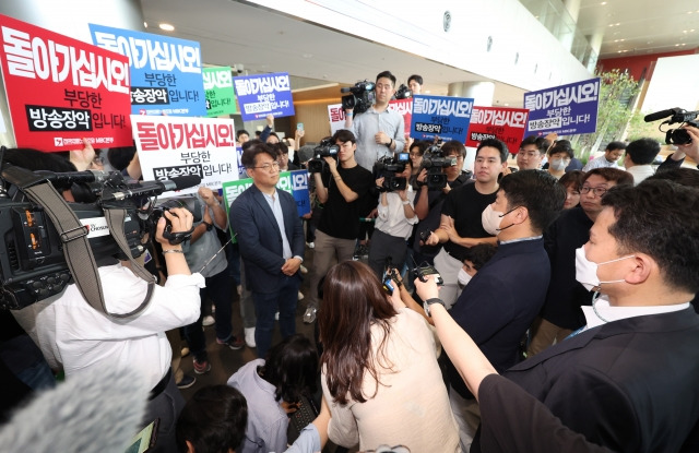 한동훈 법무부 장관의 개인정보 유출 의혹과 관련 MBC 기자 임모씨를 압수수색 중인 경찰(오른쪽)이 30일 상암동 MBC 사옥 진입을 시도하자 조합원들이 이에 항의하고 있다. 연합뉴스