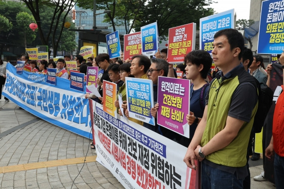 30일 서울 서초구 국제전자센터 대회의실에서 제9차 건강보험정책심의위원회가 열렸다. 비대면 진료 등에 반대하는 약사회 등 의료단체, 시민사회 단체 회원들이 회의장 앞에서 기자회견을 하고 있다. 연합뉴스