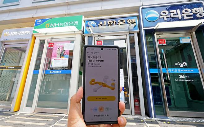 금융권의 온라인·원스톱 대환대출 플랫폼이 시행된 31일 서울 시내에 설치된 시중은행들의 ATM기와 카카오페이 대출 비교 서비스 '대출 갈아타기' 화면 모습. 연합뉴스