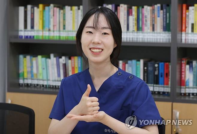 '코로나 이겨낸 국민 여러분 덕분에' (서울=연합뉴스) 이재희 기자 = 2021년 코로나19에 감염돼 음압병상에 격리된 할머니와 방호복을 입고 화투 놀이를 하는 사진으로 국민들에게 감동을 준 이수련 간호사가 30일 서울 동대문구 삼육서울병원에서 연합뉴스와 인터뷰를 마친 뒤 '존경'을 뜻하는 수어를 하고 있다. 2023.5.30 scape@yna.co.kr