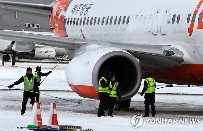 제주공항 항공기 제설작업 (제주=연합뉴스) 제주항공 지상조업체 직원들이 항공기에 붙어 있는 눈을 제거하고 있다. [연합뉴스 자료사진]