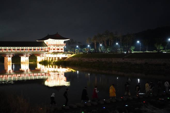 Visitors cross the step-stone bridge at Namcheon Stream in Gyeongju, North Gyeongsang Province, Tuesday. (Lee Si-jin/The Korea Herald)