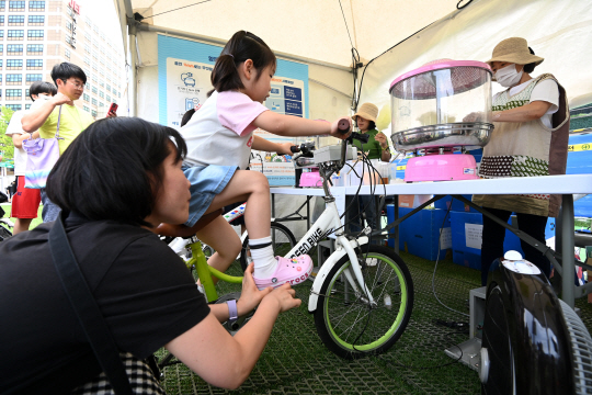 　 서울시청 앞 광장에서 열린 ‘우리가 그린(Green) 페스티벌’에서 한 어린이가 엄마와 함께 자전거 페달을 밟으며 솜사탕을 만들고 있다. 문호남 기자