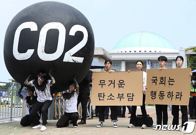 그린피스 회원들이 세계 환경의 날인 5일 서울 여의도 국회 앞에서 기후위기 대응을 촉구하는 '탄소(CO2)의 짐' 퍼포먼스를 하고 있다. 이들은 기후 위기에 대한 무관심이 계속된다면 미래세대가 과중한 탄소 감축 책임을 떠안게 된다며 국회의 대응을 촉구했다. 2023.6.5/뉴스1 ⓒ News1 신웅수 기자