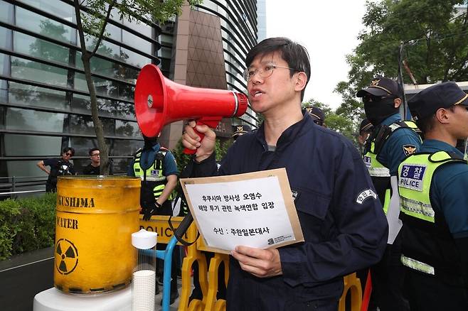 일본대사관에 들머리에서 황인철 녹색연합 기후에너지팀장이 이제석 광고연구소장이 만든 핵오염수를(상징물)담은 정수기 모형 옆에서 핵오염수 내 방사성 물질의 위험성을 대중에게 알리기 위해 일본 방사선 오염수 해양 투기를 중단하라는 기자회견을 열고 있다. 김봉규 선임기자