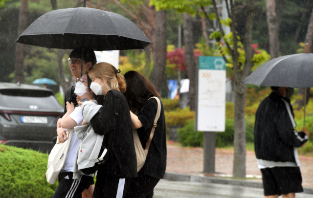 강원대학교 춘천캠퍼스에서 여러명의 학생들이 우산 하나에 의지해 강의실로 향하고 있다. [강원도민일보 자료사진]