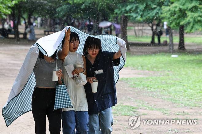 '갑자기 비가' (서울=연합뉴스) 서대연 기자 = 소나기가 내린 6일 오후 서울 성동구 서울숲에서 휴식하던 시민들이 갑자기 내린 비에 돗자리를 우산 삼아 쓰고 이동하고 있다. 2023.6.6 dwise@yna.co.kr