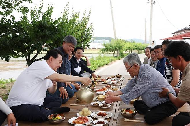 [서울=뉴시스] 윤석열 대통령이 7일 충남 부여군 임천면 꿈에영농조합법인을 방문해 모내기를 마친 뒤 주민들과 새참을 먹고 있다. (사진=대통령실 제공) 2023.06.07. photo@newsis.com *재판매 및 DB 금지 <저작권자ⓒ 공감언론 뉴시스통신사. 무단전재-재배포 금지.> /사진=뉴시스화상