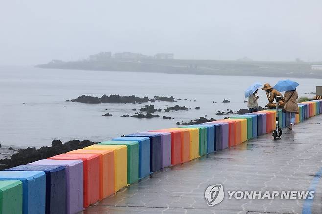 도두해안도로는 비가 와도 '인기' (제주=연합뉴스) 박지호 기자 = 이슬비가 내린 30일 오전 제주시 도두동 해안도로를 찾은 관광객들이 바다 정취를 즐기고 있다. 2023.5.30 jihopark@yna.co.kr