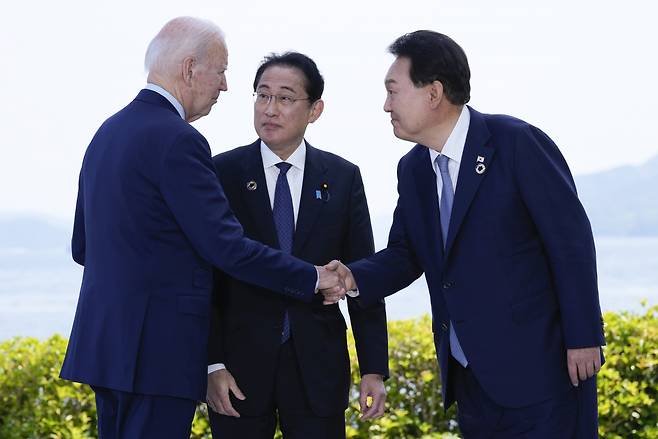 윤석열 대통령(오른쪽)과 조 바이든 미국 대통령(왼쪽)이 지난 5월 일본 히로시마에서 주요 7개국(G7) 정상회의를 계기로 열린 한미일 정상회담을 앞두고 기시다 후미오 일본 총리가 지켜보는 가운데 악수하고 있다. [연합]