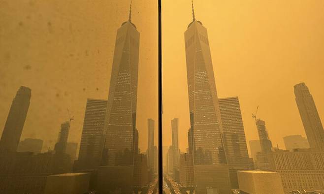 지난 7일(현지시각) 캐나다 산불로 연기가 자욱한 미국 뉴욕에서 자동차들이 월드트레이드 센터를 지나 웨스트 스트리트로 이동하는 모습이 한 건물 벽에 비치고 있다. 뉴욕=AP뉴시스