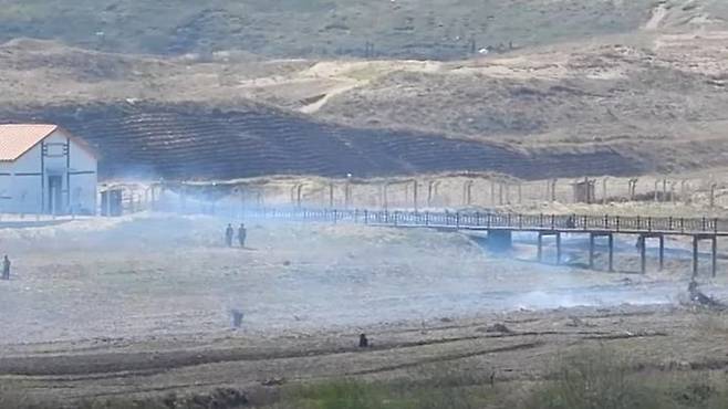 5월 말 북러 접경지역에서 촬영된 두만강 철교 너머 북한 주민들의 모습. 들판에 불을 질러 밭으로 일구거나, '새땅찾기'를 위해 군 막사 옆 경사면까지 밭으로 개척한 모습이 보인다. [사진제공=강동완 동아대 교수]