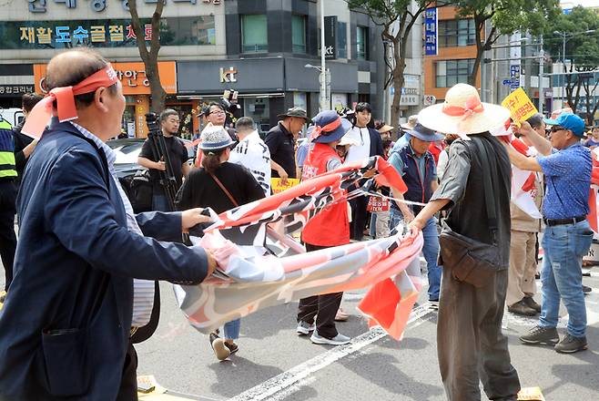 13일 오후 제주시 노형오거리에서 열린 ‘일본 핵오염수 해양투기 저지 제주 범도민대회’에서 참가자들이 욱일기를 배경으로 한 현수막을 찢고 있다 연합뉴스