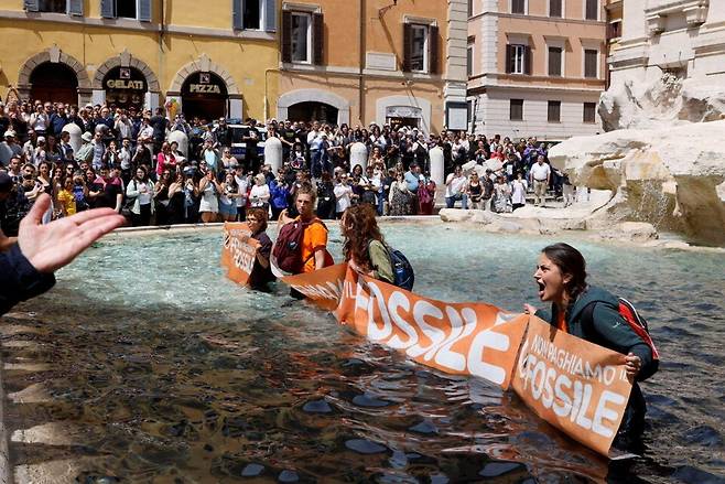 환경단체 ‘울티마 제네라치오네\'(마지막 세대) 기후활동가들이 2023년 5월21일 이탈리아 로마의 유명 관광지 트레비분수에 식물성 먹물을 뿌린 뒤 화석연료에 공적 보조금 지급을 중단하라는 시위를 벌이고 있다. 연합뉴스