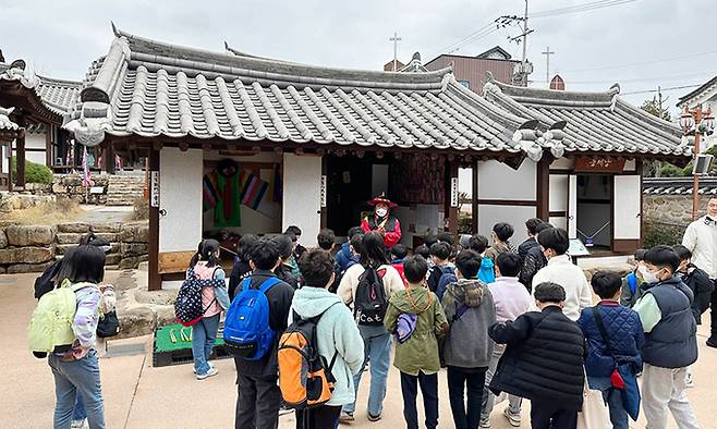 사라온 이야기마을을 방문한 학생들이 문화관광해설사의 설명을 듣고 있다. 군위군 제공