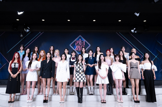Host Taeyeon and the 24 contestants of Mnet's girl group competition show ″Queendom Puzzle″ poses for a photo during a press conference on Tuesday in Seoul. [MNET]