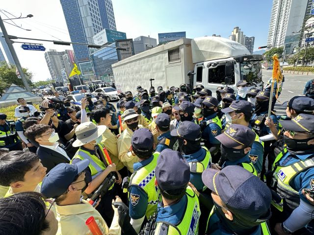 17일 오전 대구 중구 반월당역 인근에서 퀴어문화축제 측 무대차량 진입을 위해 교통 정리에 나선 경찰관들과 이를 막으려는 대구시 공무원들이 대치하고 있다. 경찰 뒤쪽으로 무대차량이 진입하고 있다. 연합뉴스