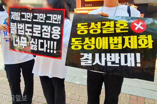 퀴어축제에 반대하는 맞불집회 참가자들이 17일 대구 중구 동성로 일대에서 '불법도로점용' 등이 적힌 피켓을 들고 있다. 류수현 기자
