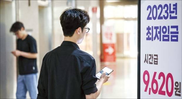 18일 서울 마포구 서부고용복지플러스센터에서 한 근로자가 올해 최저임금이 적힌 입간판 앞을 지나고 있다.    최혁 기자