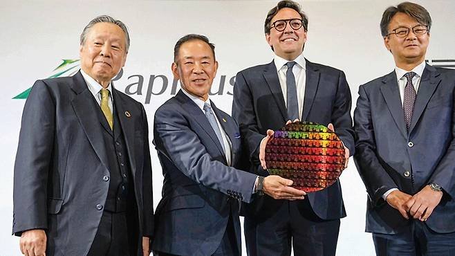 일본 반도체 기업 라피더스의 고이케 아쓰요시(왼쪽에서 둘째) 사장이 미국 IBM 다리오 길(왼쪽에서 셋째) 수석부사장과 지난해 12월 일본 도쿄에서 ‘차세대 반도체 개발 협약’을 맺은 뒤 반도체 웨이퍼를 들고 기념촬영을 하고 있다. 양사는 2027년까지 최첨단 2나노 반도체를 생산한다는 계획이다./교도연합뉴스