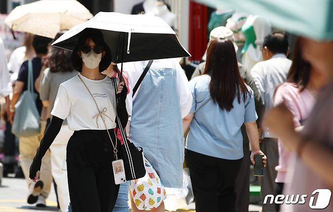 서울 낮 최고 기온이 33도에 육박한 무더운 날씨를 보인 19일 서울 명동거리에서 시민이 양산을 들고 걷고 있다. 2023.6.19/뉴스1 ⓒ News1 김민지 기자