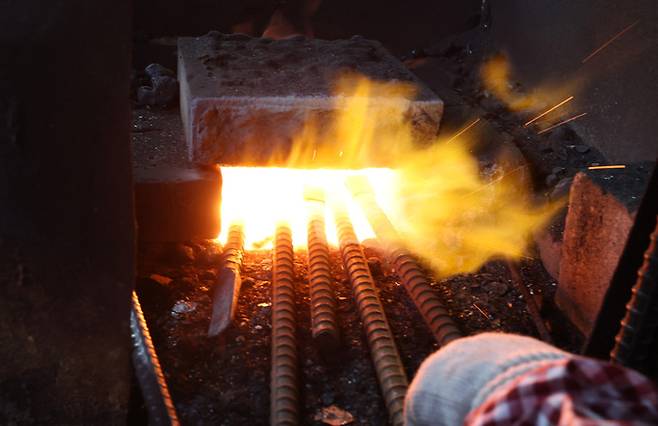 끌을 제작하는 첫 작업으로 1000도가 넘는 고열의 가마에 철근을 달구어 날 모양을 만드는 단조작업을 하고 있다.