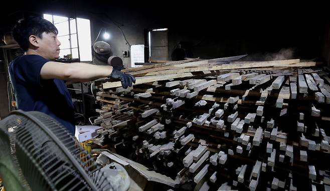 전수자인 아들 김민규씨가 끌 자루에 사용되는 참나무를 고르고 있다. 참나무는 3년 이상 말려야 오래간다.