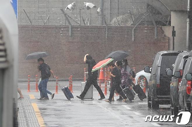 올해 첫 장맛비가 본격적으로 내리는 25일 제주국제공항에서 우산을 쓴 관광객들이 발걸음을 옮기고 있다.2023.6.25/뉴스1 ⓒ News1 강승남 기자