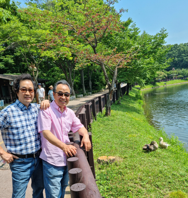 오리들이 한가롭게 노는 율동공원을 배경으로 필자와 형님 김재삼(오른쪽) 씨가 정겹게 미소 지으며 서 있다.