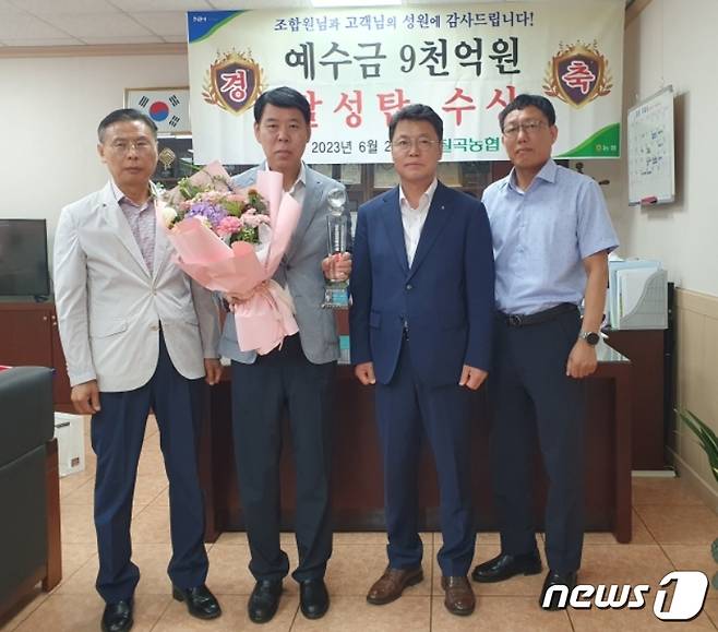 배상균 대구 칠곡농협 조합장(왼쪽 두번째)이 상호금융 예수금 9000억원 달성탑과 꽃다발을 들고 기념사진을 촬영하고 있다.(칠곡농협 제공)