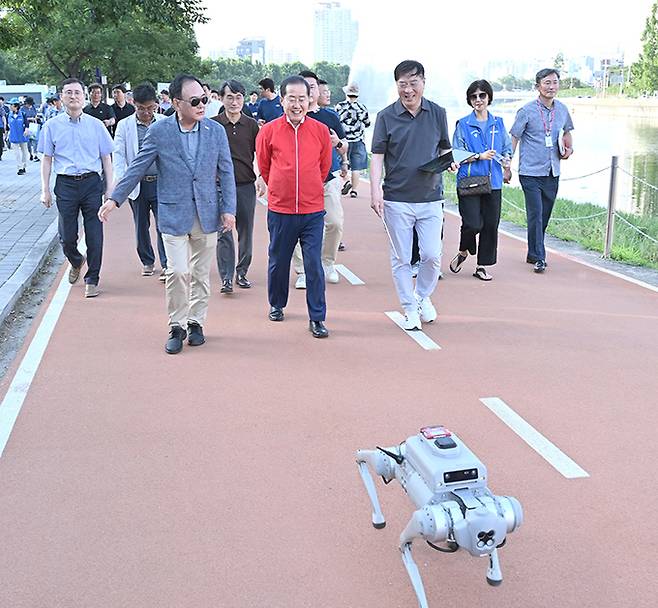 홍준표 대구시장(앞줄 가운데)과 이만규 대구시의회 의장(〃 왼쪽)이 로봇 개와 함께 신천 둔치 보행로를 걷고 있다. 대구시 제공