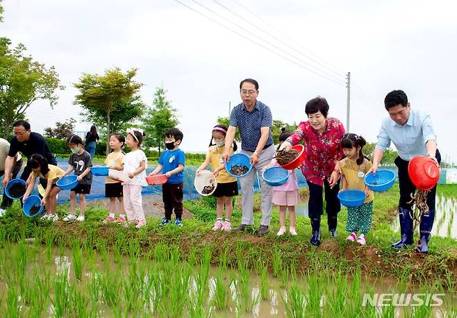 [제천=뉴시스] 이도근 기자= 29일 충북 제천시 모산동 의림지뜰 육묘장 일원에서 김창규 제천시장과 이정임 제천시의장이 지역농업인, 어린이들과 함께 친환경 벼 재배를 위한 우렁이와 미꾸라지 등을 방사하고 있다. 이날 행사에서 오리 200마리, 미꾸라지·메기 각 100㎏, 우렁이 50㎏ 등이 방사됐다. 이들은 물속 잡초 생장을 억제하고, 양분을 토양에 전파해 벼 생육을 돕는 역할을 한다. (사진=제천시 제공) 2023.6.29. photo@newsis.com *재판매 및 DB 금지