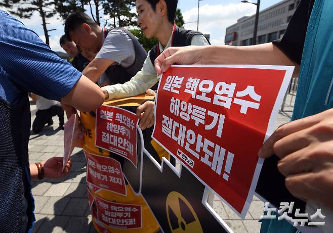 지난 22일 서울 용산구 전쟁기념관 앞에서 열린 '일본 핵 오염수 해양투기 저지 투쟁 선포 민주노총 전국동시다발 기자회견' 참석자들이 드럼통에 스티커를 부착하는 상징의식을 하고 있다. 황진환 기자