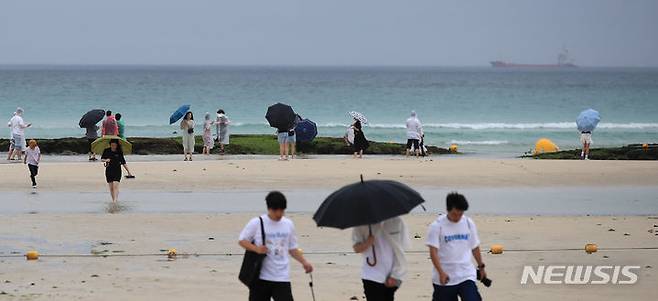 [제주=뉴시스] 우장호 기자 = 제주도 전역에 호우주의보가 내려진 30일 오후 제주시 한림읍 협재해수욕장을 찾은 관광객들이 궂은 날씨에도 해변을 거닐며 즐거운 시간을 보내고 있다. 기상청에 따르면 정체전선상에서 발달하는 저기압 영향으로 7월1일 오전까지 제주지역에 비가 내리겠다. 2023.06.30. woo1223@newsis.com