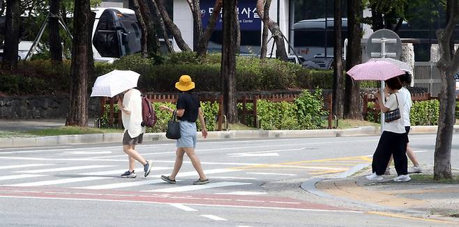 폭염주의보가 발효 중인 3일 오전 대전 서구 대전광역시청 인근에서 시민들이 햇살을 피하기 위해 양산과 우산, 모자를 쓴 채 길을 걷고 있다. 연합뉴스