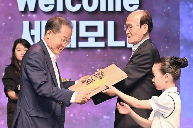 3일 군위군민 대표 두 명이 홍준표 대구시장에게 군위군 브랜드 슬로건인 ‘삼국유사의 고장, 군위’ 목판을 전달하고 있다. (대구시 제공) 2023.07.03