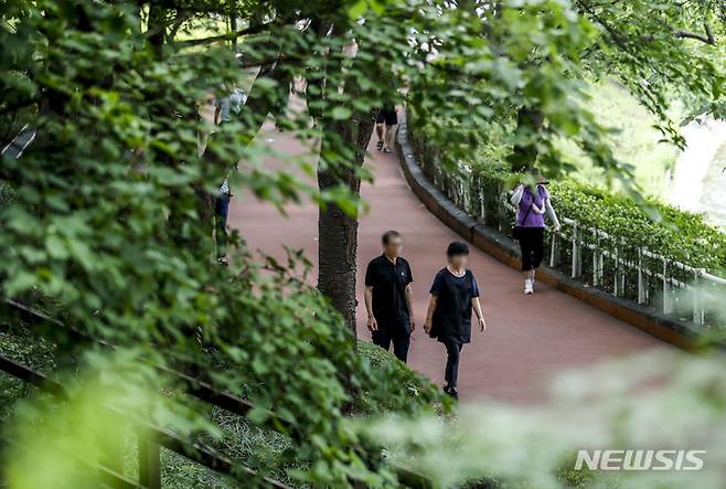 [서울=뉴시스] 정병혁 기자 = 더운 날씨가 이어진 3일  서울 송파구 석촌호수를 찾은 시민들이 나무 그늘 아래에서 이동하고 있다. 2023.07.03. jhope@newsis.com