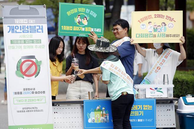 15일 광주 북구청 청소행정과 자원순환팀 직원들이 구청 앞 광장에서 탄소중립 실천을 위해 직원들과 주민을 대상으로 청사 내 1회용품 반입 제한 캠페인을 펼치고 있다. [연합]