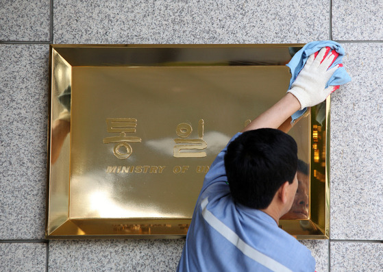 An employee cleans the Ministry of Unification signboard in front of the central government complex in Gwanghwamun, central Seoul. [JOONGANG PHOTOS]