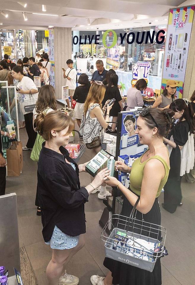 올리브영 매장을 찾은 외국인들이 K뷰티 상품들을 살펴보고 있는 모습(사진=올리브영 제공) *재판매 및 DB 금지